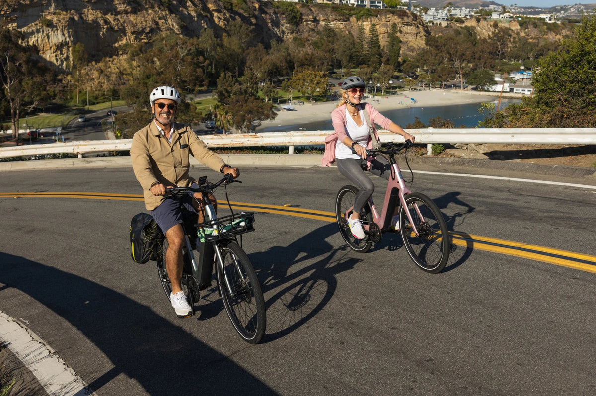 Two riders on Aventon Pace 5 REC e-bikes on a coastal road